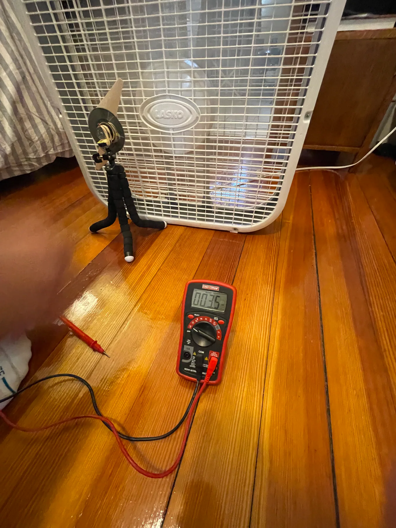 Wind turbine positioned in front of a box fan with a multimeter.